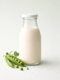 En glasflaska med ärtmjölk. Bredvid ligger en ärtskida. 